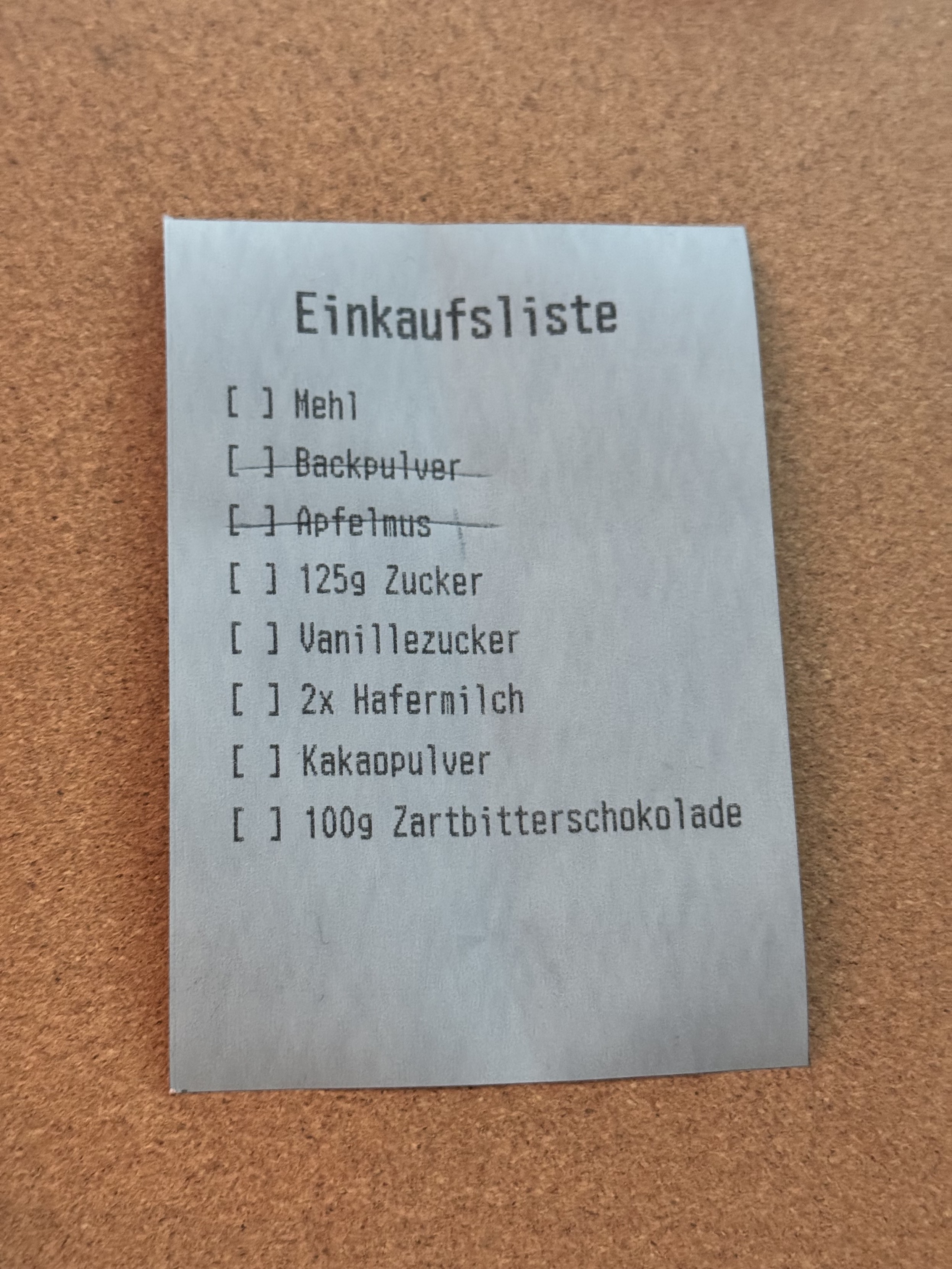 Ein Einkaufszettel gedruckt auf Kassenzettelpapier. Die einzelnen Elemente sind irrelevant, aber zwei sind händisch durchgestrichen.