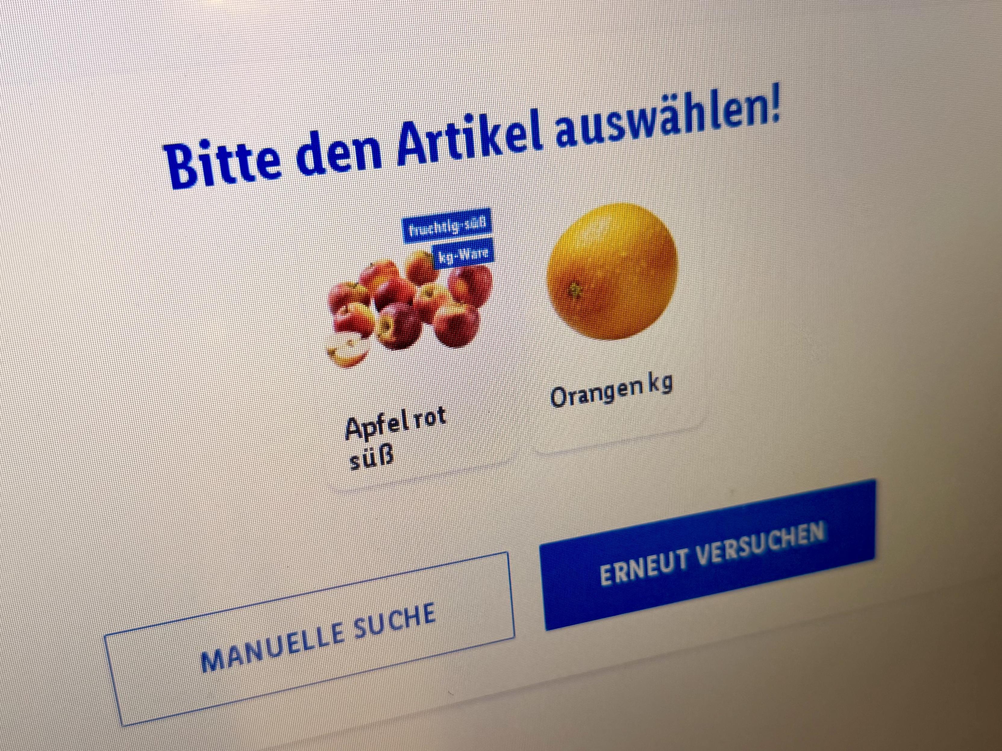 Bildschirm der Selbstbedienungskasse mit der Artikelauswahl "Apfel rot süß" oder "Orangen". 